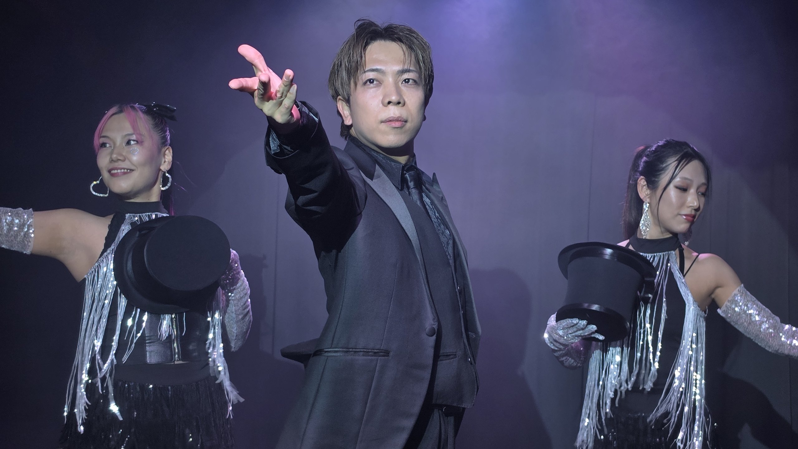 ステージでショーを始めるマジシャン黒崎博斗とダンサー2名